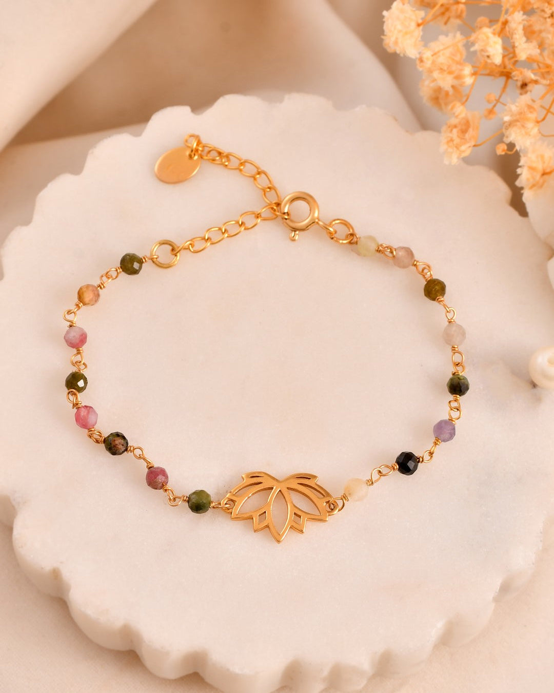 Gold bracelet with colorful beads on a decorative plate